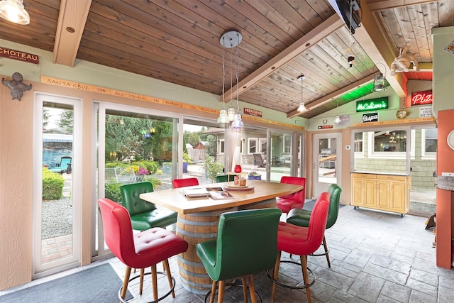 dining room with wood ceiling, lofted ceiling with beams, and stone tile floors