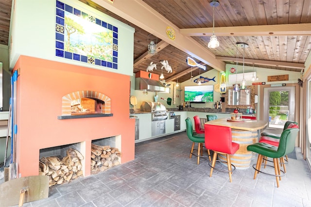 dining room featuring vaulted ceiling with beams, stone finish flooring, a fireplace, and wood ceiling