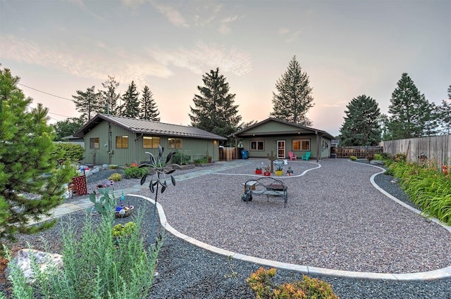 back of property at dusk with an outbuilding, metal roof, a fenced backyard, a standing seam roof, and a patio area