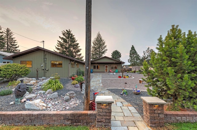 back of house at dusk featuring a patio, board and batten siding, and fence