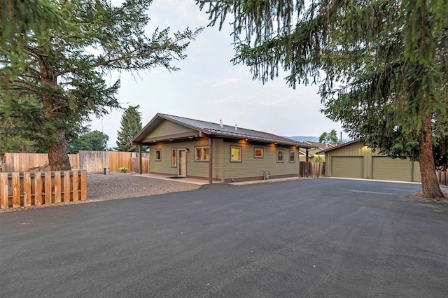 view of front of home with a detached garage, fence, and an outbuilding