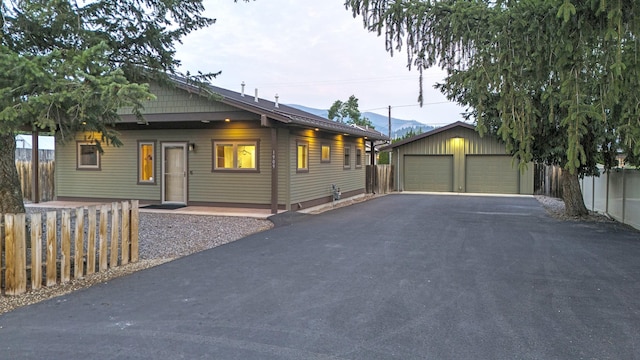 view of front of house with a garage, fence, a mountain view, and an outbuilding