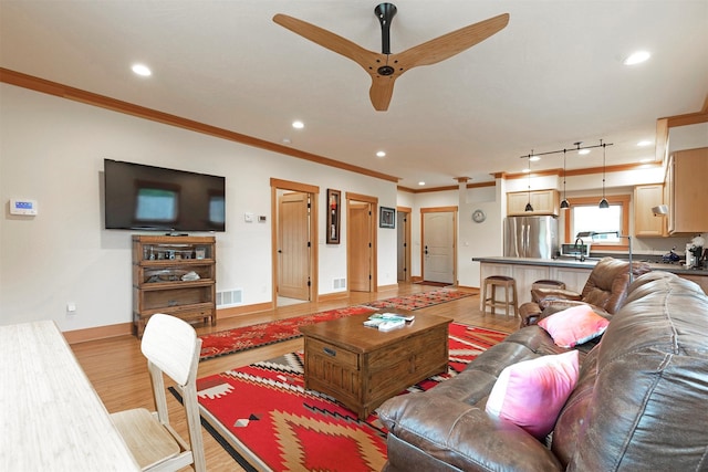 living area with crown molding, recessed lighting, visible vents, light wood-style flooring, and baseboards