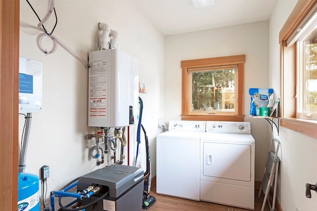 clothes washing area with tankless water heater, laundry area, separate washer and dryer, wood finished floors, and a heating unit