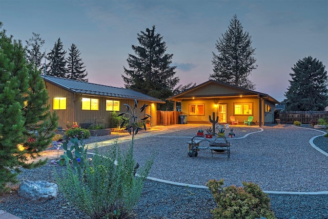 back of house at dusk with metal roof, a standing seam roof, a patio, and fence