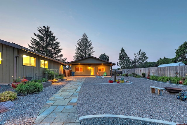 back of property at dusk featuring board and batten siding, a patio area, and a fenced backyard