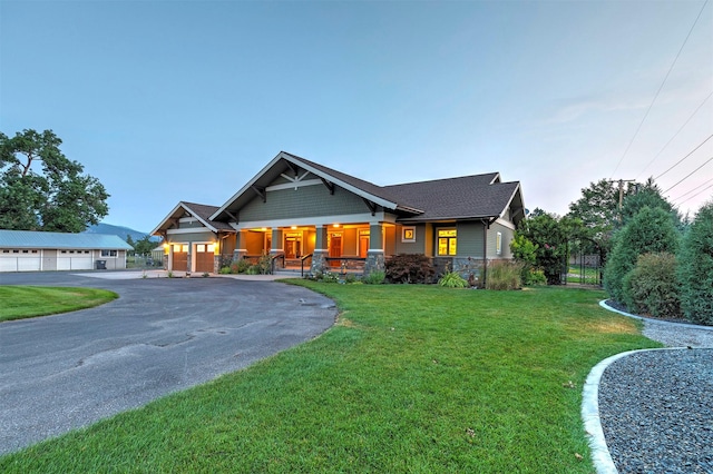 craftsman-style house with a porch, a front yard, stone siding, and a garage