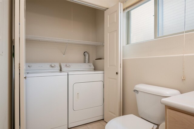 clothes washing area with independent washer and dryer and light tile patterned floors