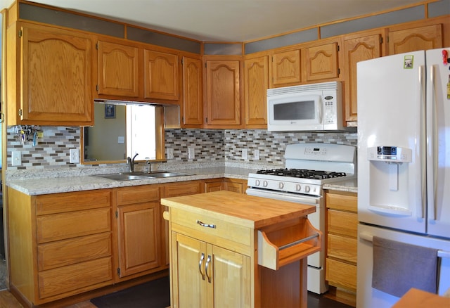 kitchen featuring decorative backsplash, white appliances, a center island, and sink