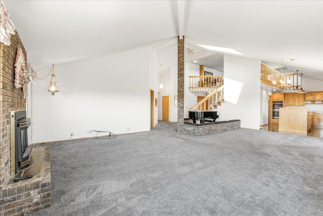 unfurnished living room featuring carpet floors, beam ceiling, stairway, a brick fireplace, and high vaulted ceiling