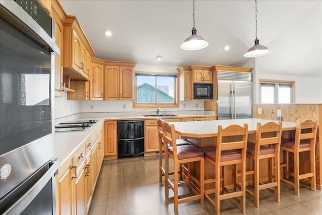 kitchen featuring black appliances, a breakfast bar area, light countertops, and a sink