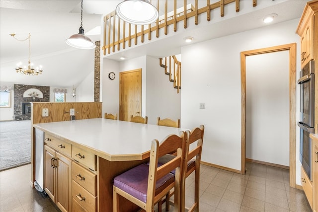 kitchen featuring a kitchen island, light countertops, double oven, a kitchen bar, and a notable chandelier