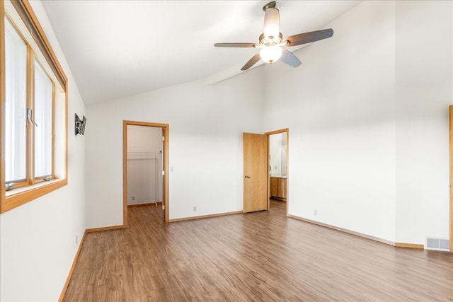 empty room with visible vents, ceiling fan, high vaulted ceiling, light wood-type flooring, and baseboards