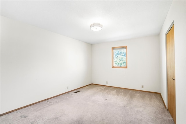 spare room with light carpet, visible vents, and baseboards