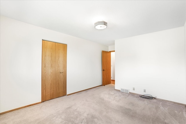 unfurnished bedroom featuring light colored carpet, a closet, visible vents, and baseboards