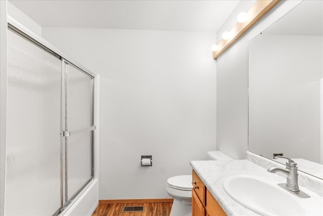 bathroom with visible vents, toilet, vanity, wood finished floors, and baseboards