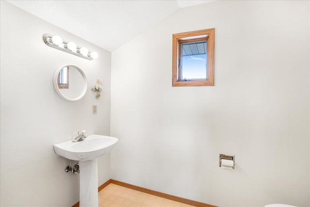 bathroom with baseboards, vaulted ceiling, a sink, and tile patterned floors