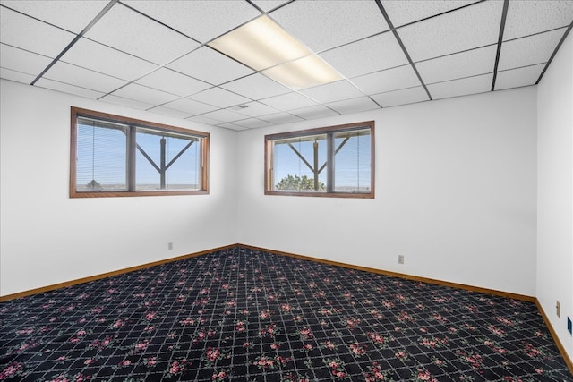 basement with a drop ceiling, carpet flooring, and baseboards