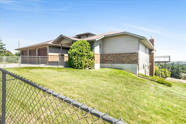 view of property exterior with a garage, brick siding, a lawn, and fence