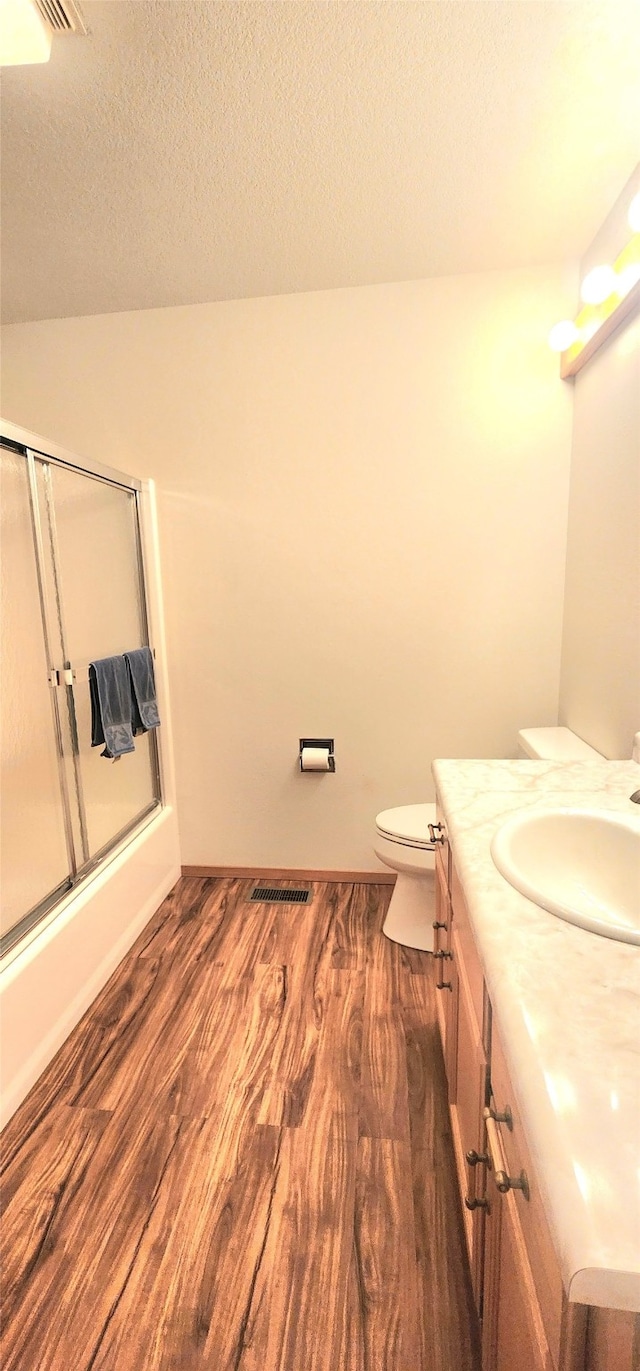 bathroom featuring a textured ceiling, toilet, wood finished floors, vanity, and visible vents