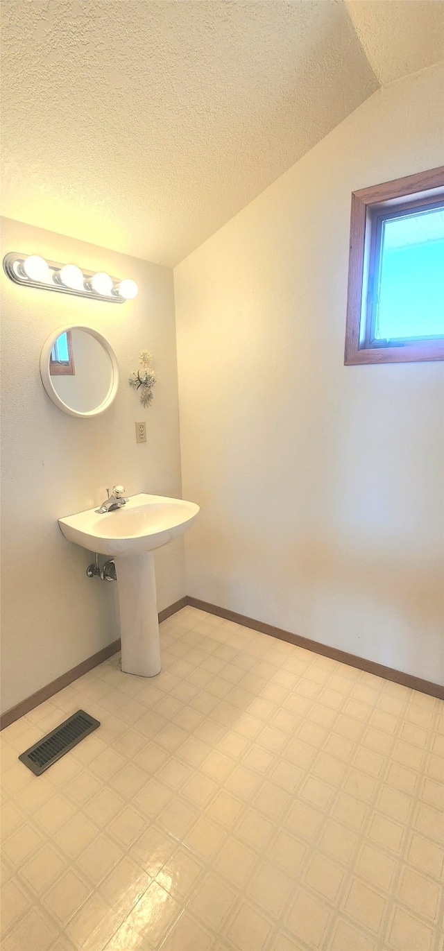 bathroom featuring a textured ceiling, tile patterned floors, visible vents, and baseboards