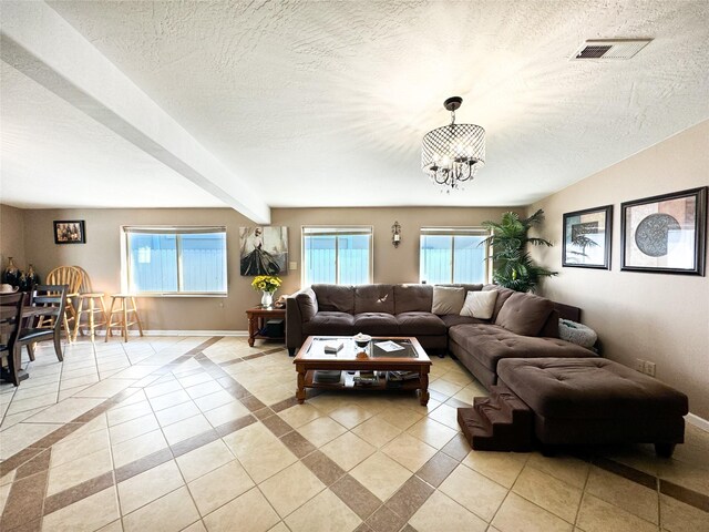 living room featuring visible vents, baseboards, light tile patterned flooring, a notable chandelier, and a textured ceiling