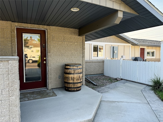 entrance to property featuring brick siding and fence