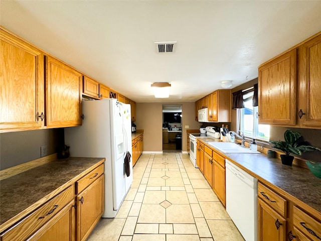 kitchen with white appliances, light tile patterned floors, brown cabinetry, visible vents, and a sink