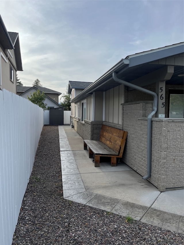 view of side of home featuring brick siding, a fenced backyard, and a patio area