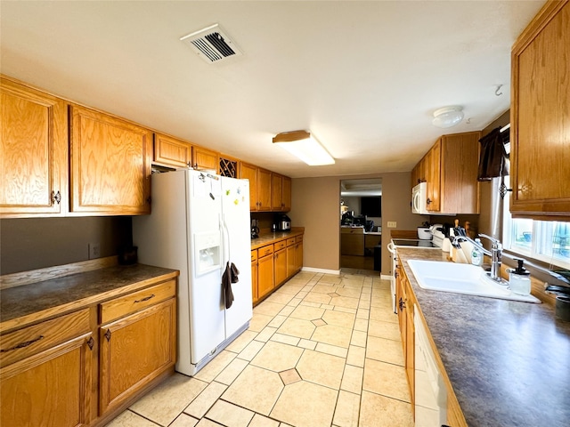 kitchen with a sink, visible vents, white appliances, and brown cabinets