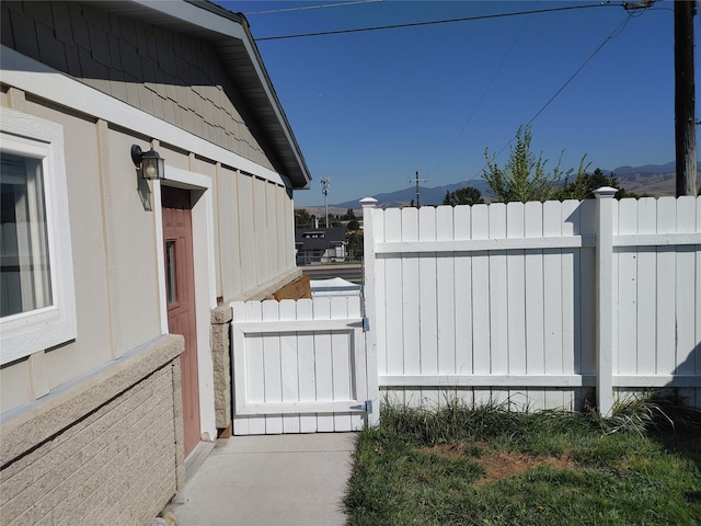 view of side of property featuring a gate, fence, and a mountain view