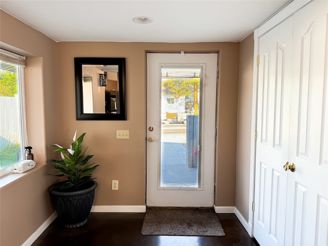 doorway with dark wood finished floors, a healthy amount of sunlight, and baseboards