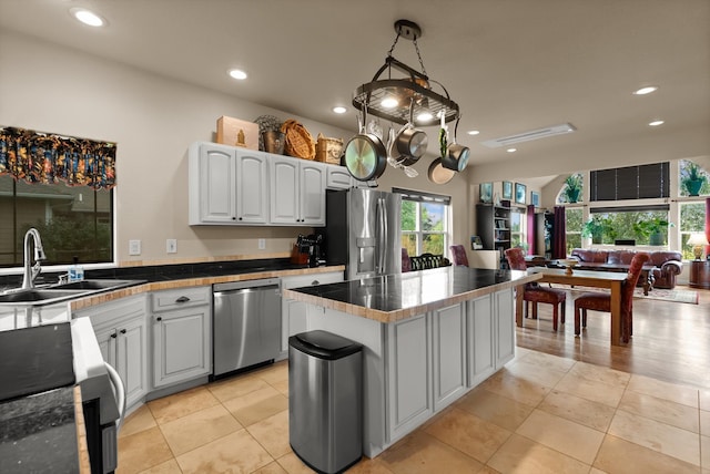 kitchen featuring white cabinets, sink, a center island, light tile patterned flooring, and stainless steel appliances