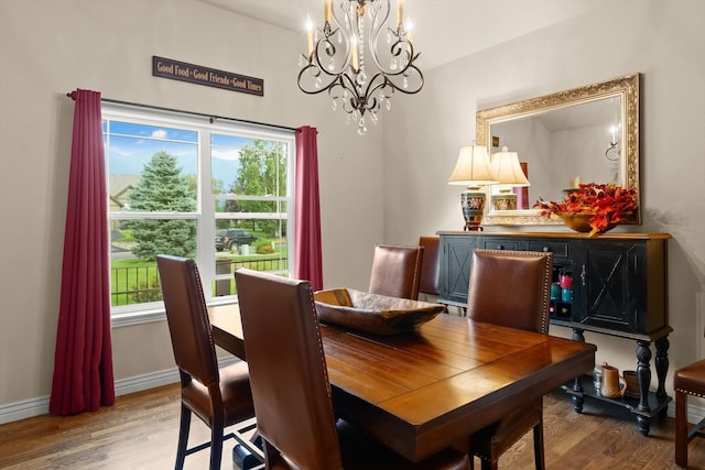 dining area with a wealth of natural light, an inviting chandelier, and wood-type flooring