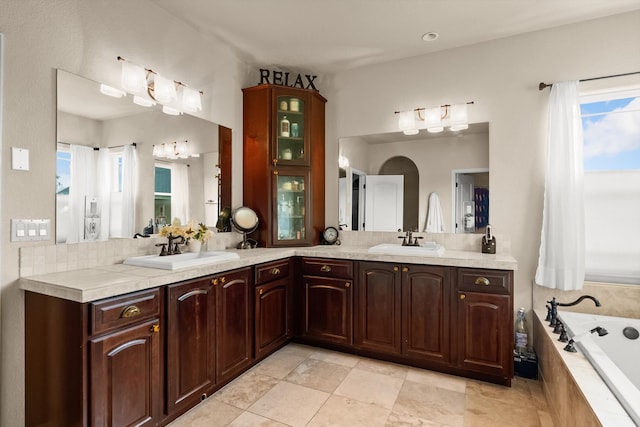 bathroom with tile patterned flooring, tiled tub, and vanity