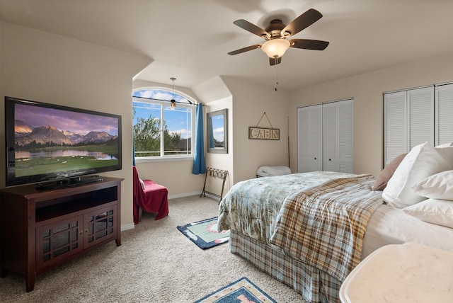 carpeted bedroom featuring ceiling fan, two closets, and vaulted ceiling