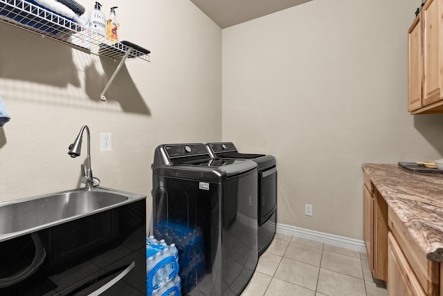 clothes washing area with separate washer and dryer, sink, cabinets, light tile patterned floors, and a barn door