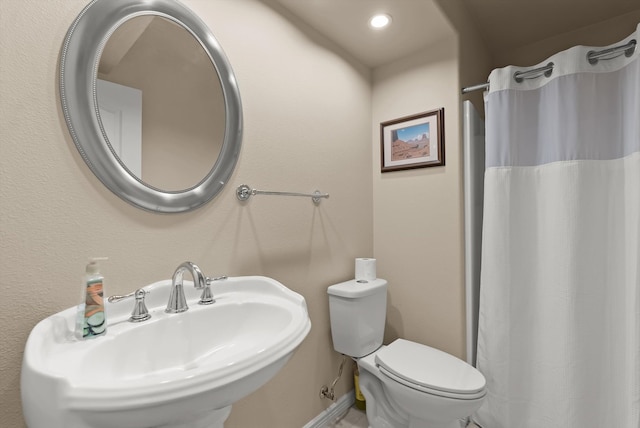 bathroom with sink, curtained shower, and toilet