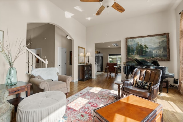 living room with hardwood / wood-style floors, high vaulted ceiling, and ceiling fan