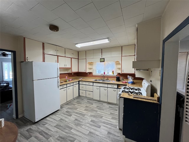 kitchen with white cabinetry, sink, light wood-type flooring, and white appliances