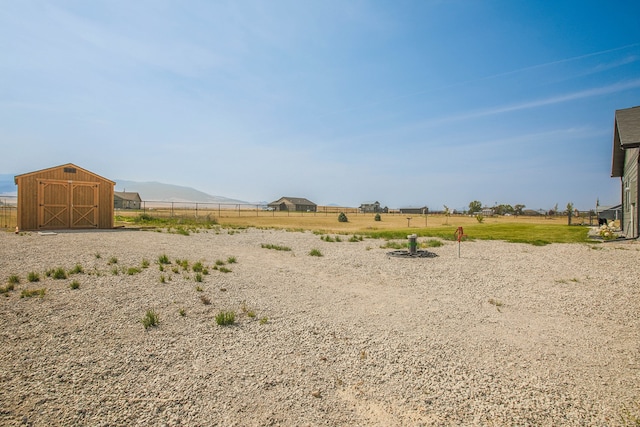 view of yard featuring a mountain view, a storage shed, and a rural view