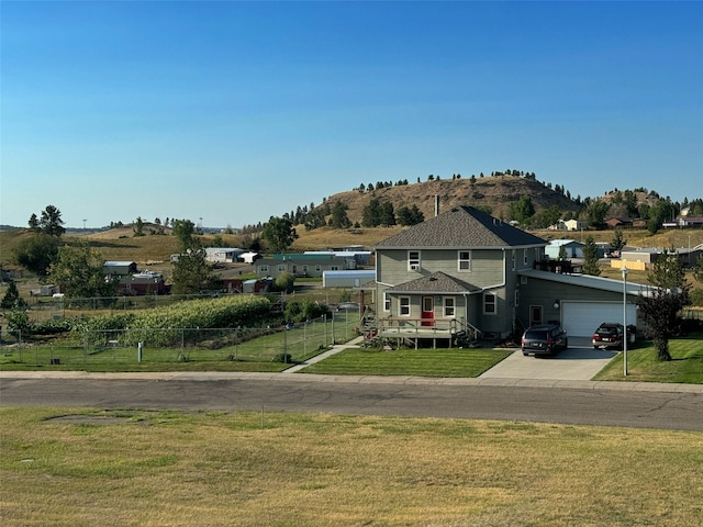 view of front of property with a fenced front yard, a mountain view, a garage, driveway, and a front yard