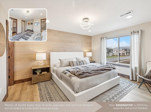 bedroom featuring wood-type flooring, a textured ceiling, and wooden walls