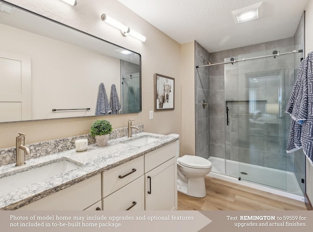 bathroom featuring vanity, a textured ceiling, hardwood / wood-style floors, toilet, and a shower with shower door