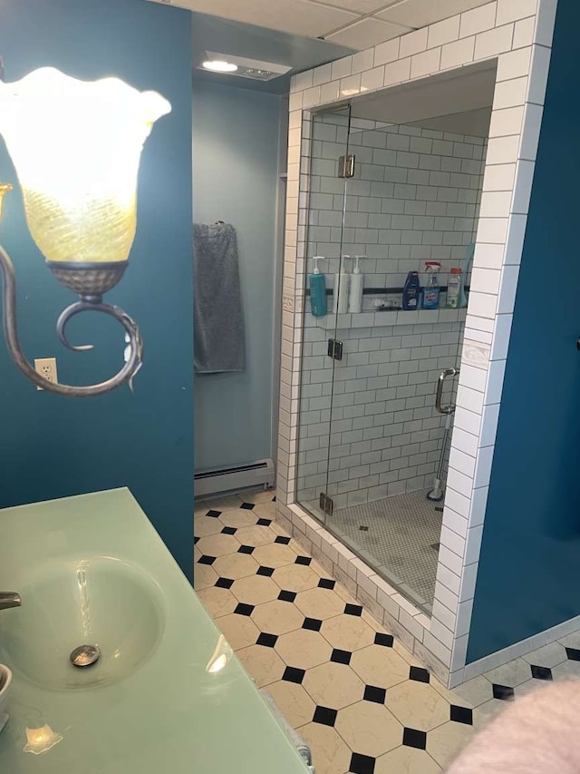 bathroom with tile patterned flooring, a baseboard radiator, a shower with door, and vanity