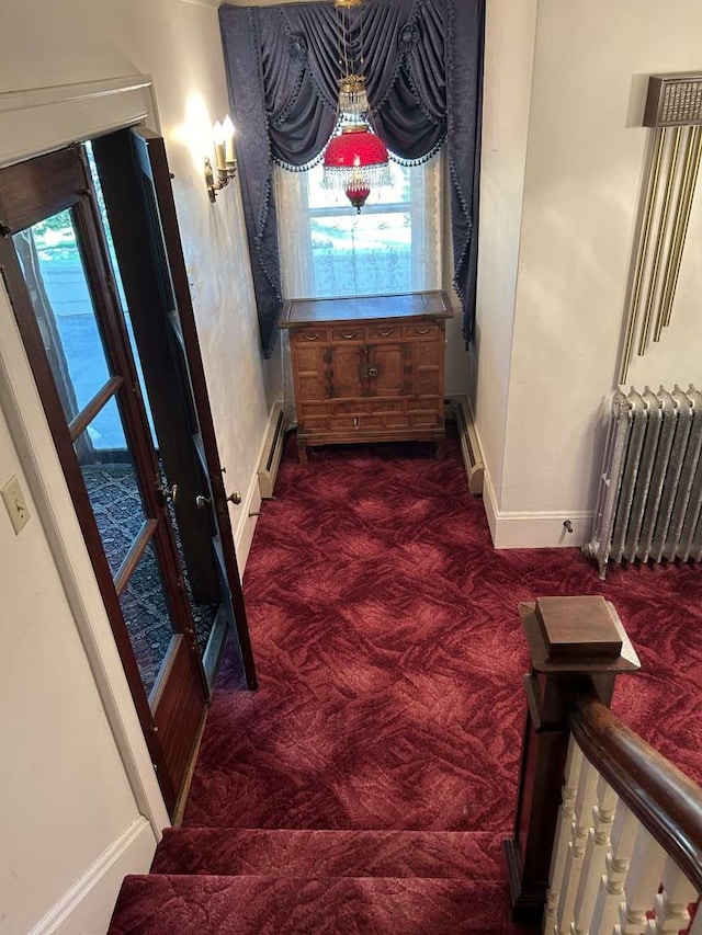 stairway with a baseboard heating unit, carpet, radiator, and a chandelier