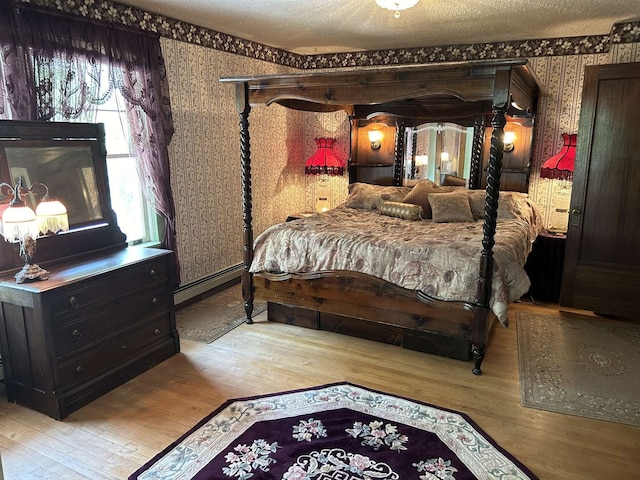 bedroom featuring a baseboard heating unit, a textured ceiling, and light hardwood / wood-style floors