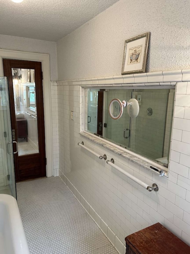 bathroom featuring tile walls, an enclosed shower, and a textured ceiling