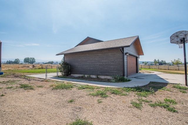 view of side of home featuring a garage, a rural view, and an outbuilding