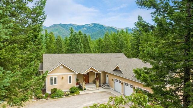 1550 Rolling Ridge Loop, Kalispell, MT 59901 - view of front of home featuring asphalt driveway, a garage, a shingled roof, a mountain view, and a forest view